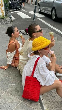 three women sitting on the sidewalk eating ice cream