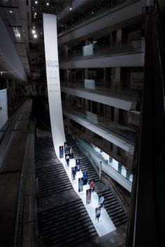 an escalator in a building with people walking up and down it at night