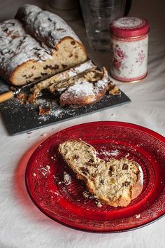 a red plate with a piece of bread on top of it next to a loaf of bread