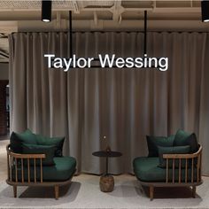 two green chairs sitting next to each other in front of a curtained wall with the words taylor westing on it