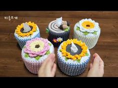 four decorated cupcakes sitting on top of a wooden table