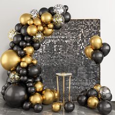 a black and gold balloon arch next to a table with silver and gold balloons on it