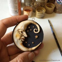 a person holding a small clay moon with a man's face on it