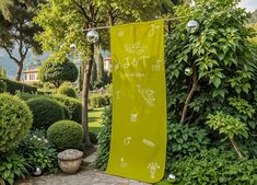 a yellow banner hanging in the middle of a garden