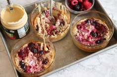 three desserts in bowls on a tray with raspberries