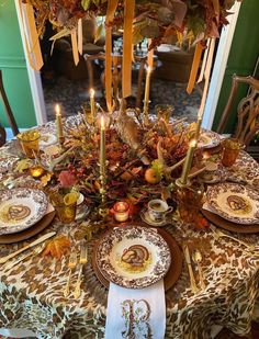 the table is set with plates and candles