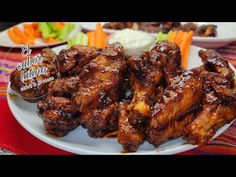 chicken wings on a white plate with carrots and celery