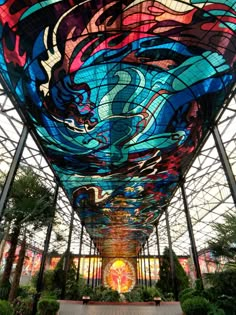 the inside of a building that has a large glass ceiling with colorful designs on it