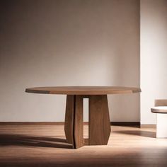 a round wooden table sitting on top of a hard wood floor next to a white chair