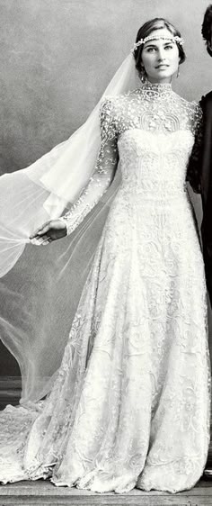 black and white photo of bride and groom posing for wedding portrait with veil blowing in wind