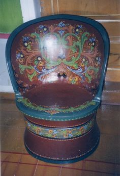 an old wooden chair with painted designs on it's seat and back rests on the floor