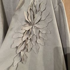 a close up of a dress with flowers on the front and back, made out of silver fabric