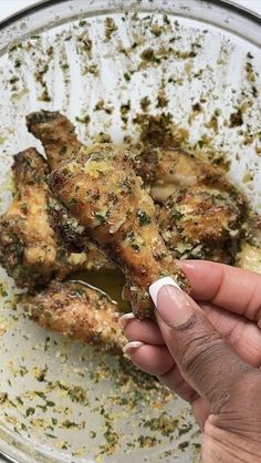 someone is holding their finger up to some food in a glass bowl on the table