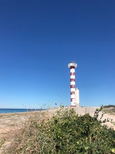 a red and white lighthouse sitting on top of a sandy beach