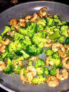 broccoli and shrimp are being cooked in a wok on the stove top