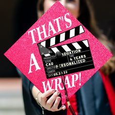 a woman holding a pink graduation cap that says, that's a wrap