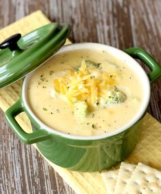 there is a bowl of soup with cheese on the top and crackers next to it