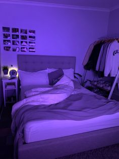 a bed in a room with purple lighting on the walls and clothes hanging up to dry