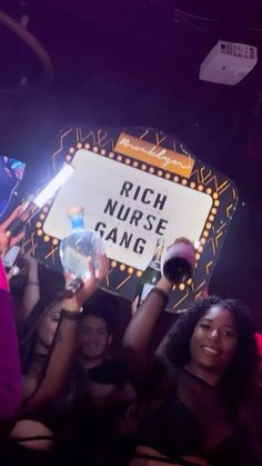 a group of people holding up signs in front of a crowd at a nightclub or club