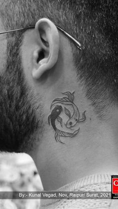 a black and white photo of a man's neck with a fish tattoo on it