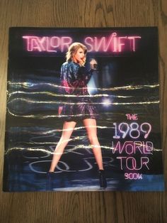 taylor swift the 1989 world tour book is displayed on a white surface with an image of taylor swift holding a microphone