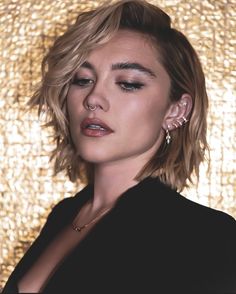 a close up of a person wearing earrings and a black shirt with gold background