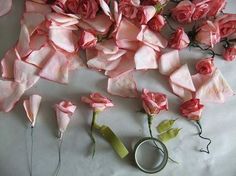 some pink flowers and scissors on a white table cloth with paper roses in the middle