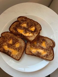 four pieces of toast with cheese on them sitting on a white plate next to a cup