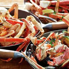 several pans filled with different types of crab legs and seafood on serving utensils