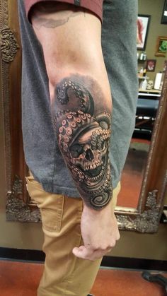 a man's arm with a skull and crown tattoo on the left side of his leg