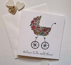 a card with a baby carriage on it and two hearts attached to the back, sitting next to each other