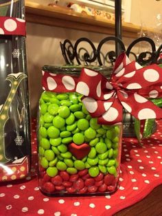 a glass jar filled with green and red candies next to a christmas present box