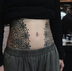 a woman's stomach with an intricate tattoo on her lower body and side part