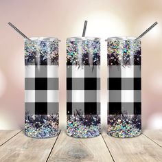 two black and white checkered tumblers with straws in them on a wooden table