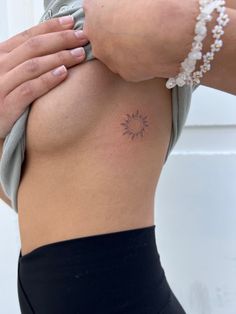 a woman's lower back with a sun tattoo on her left side ribcage