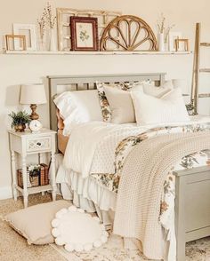 a bed with white sheets and pillows on top of it next to a table with pictures