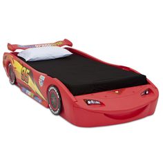 a red race car bed with black mattress and pillow on the top, in front of a white background