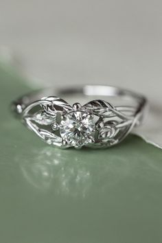 a close up view of a diamond ring on a green tablecloth with white background