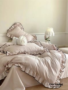 a bed with pink comforter and pillows on it in front of a white wall