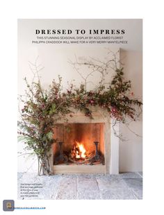 the fireplace is decorated with greenery and flowers on it's mantle, along with an open fire