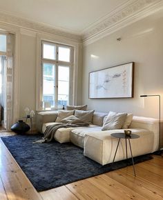 a living room filled with furniture and a large window next to a rug on top of a hard wood floor