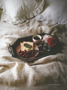 a tray with food on top of a bed next to pillows and pillowcases