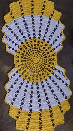 a crocheted doily with yellow and white circles on the bottom is shown