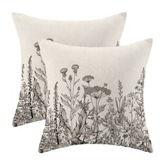 two pillows with black and white floral designs on the front, one is made out of linen