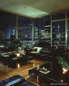 a living room filled with lots of furniture and tall buildings in the background at night