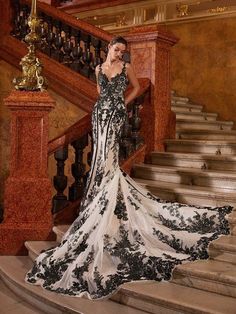 a woman in a black and white dress standing on some stairs