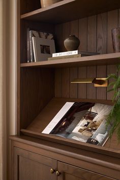 a wooden book shelf with books on top of it next to a potted plant