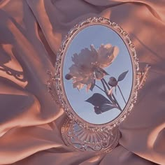 an image of a mirror with flowers in it on a pink cloth covered tablecloth