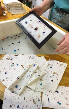 a woman is making paper with colored confetti on it and holding a black frame