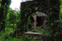 an old stone building with vines growing around it's walls and doorways in the woods